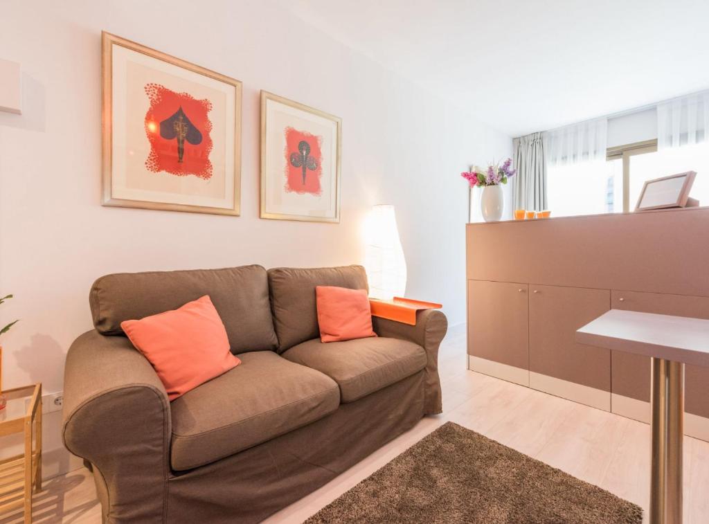 sala de estar con sofá marrón con almohadas de color naranja en Villanueva III, en Madrid