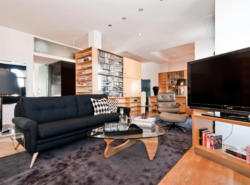 sala de estar con sofá negro y TV en Apartamento en pleno Gran Via I en Madrid