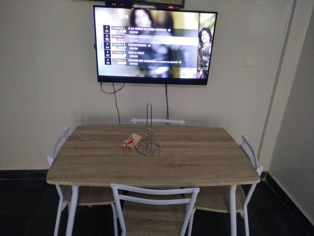 a wooden table with a television on a wall at Appartement Beau Séjour in Dakar