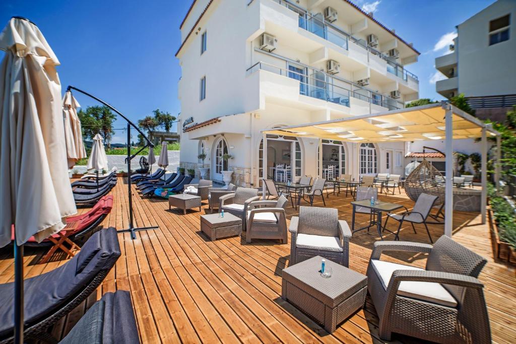 a wooden deck with chairs and tables and umbrellas at San Georgio Boutique Hotel in Agios Georgios Pagon