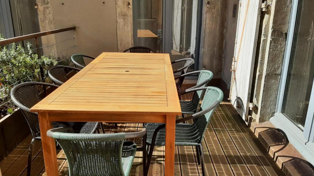 a wooden table and chairs on a balcony at Le Selamat, Logis XL au calme avec Terrasse in Carcassonne