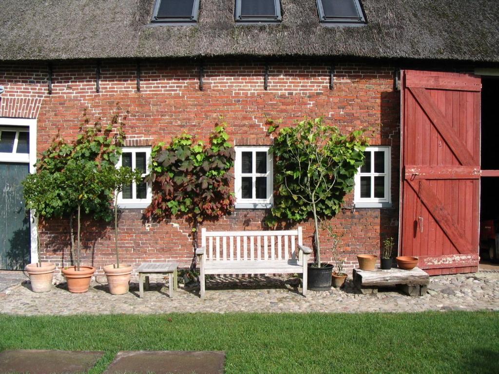 erfgoed Rikkerda في Lutjegast: مقعد أمام مبنى من الطوب يحتوي على نباتات