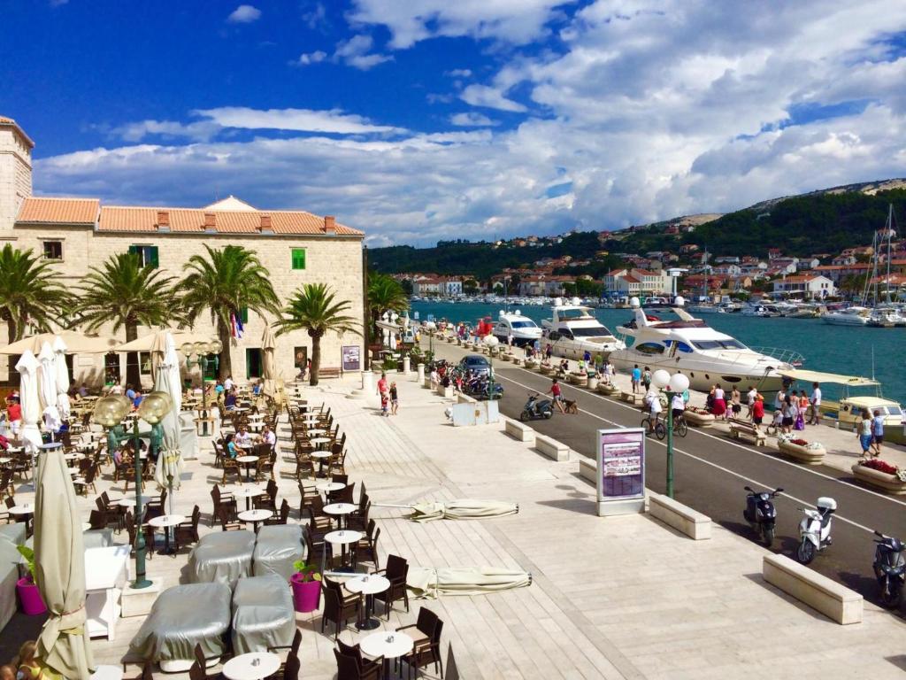 a group of tables and chairs on a sidewalk next to a marina at Apartment Palace in Rab