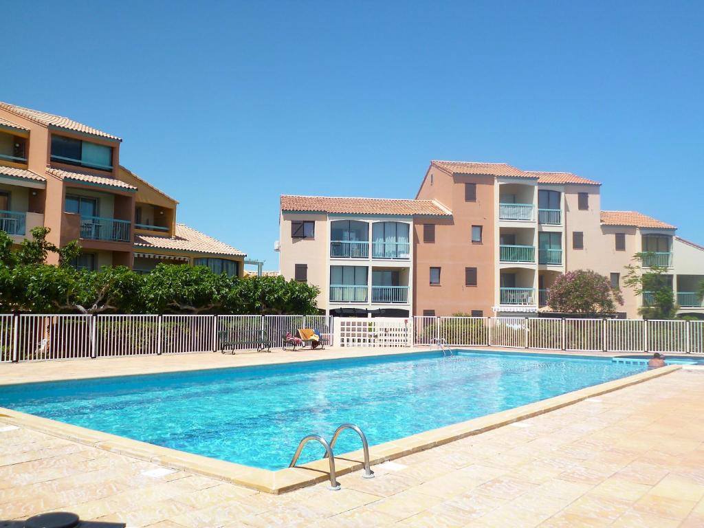 a swimming pool in front of some apartment buildings at Apartment Les Barcarelles by Interhome in Le Barcarès