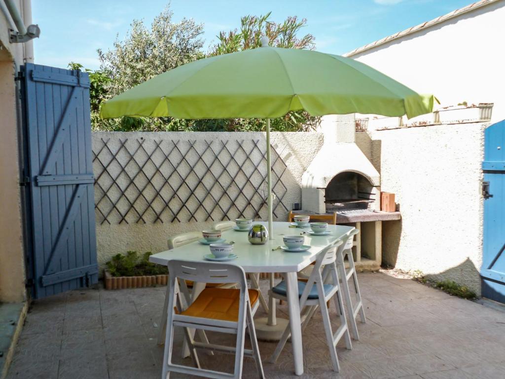 ル・バルカレスにあるHoliday Home Les Jardins du Barcarès-1 by Interhomeのパティオ(パラソルの下にテーブルと椅子付)