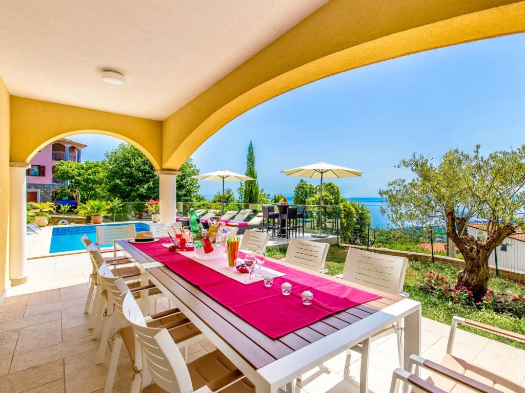 a patio with a table and chairs and a pool at Holiday Home Villa Orhidea by Interhome in (( Marčići ))