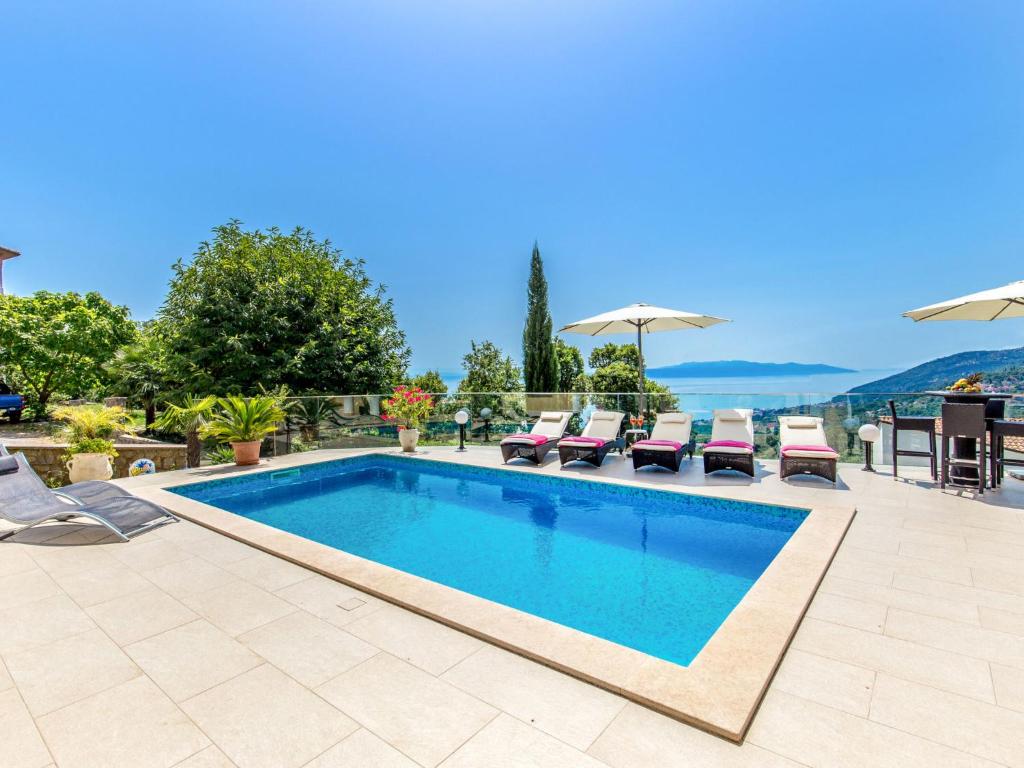 a pool with chairs and umbrellas on a patio at Holiday Home Villa Orhidea by Interhome in (( Marčići ))