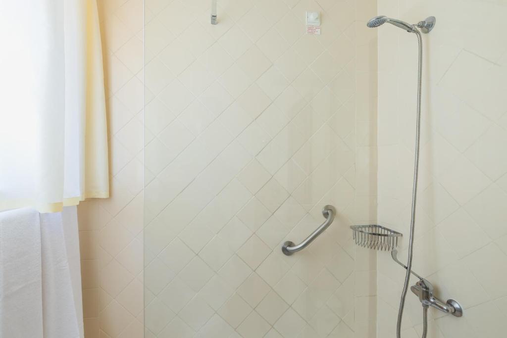 a shower stall in a bathroom with a shower curtain at Hotel Residencial Colibri in Costa da Caparica