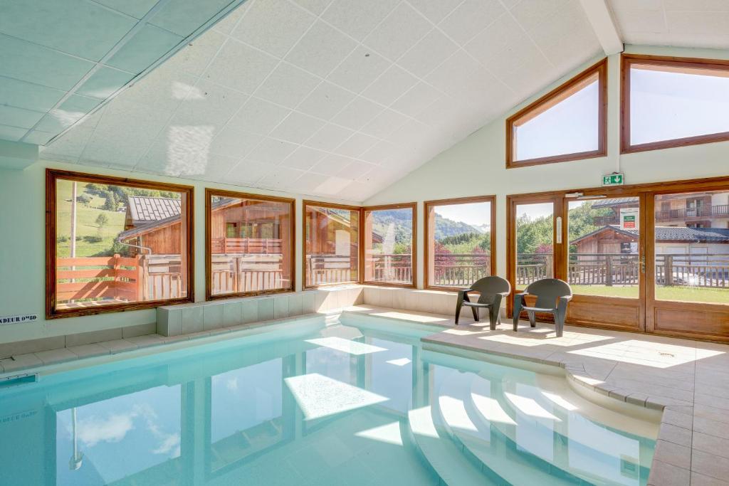 - une piscine avec 2 chaises et des fenêtres dans l'établissement Le Chevreuil - 3 chambres, terrasse, piscine, à Flumet