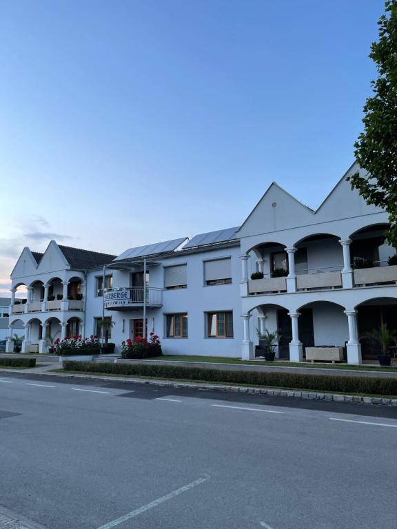 een groot wit gebouw aan de straatkant bij Die Herberge in Podersdorf am See