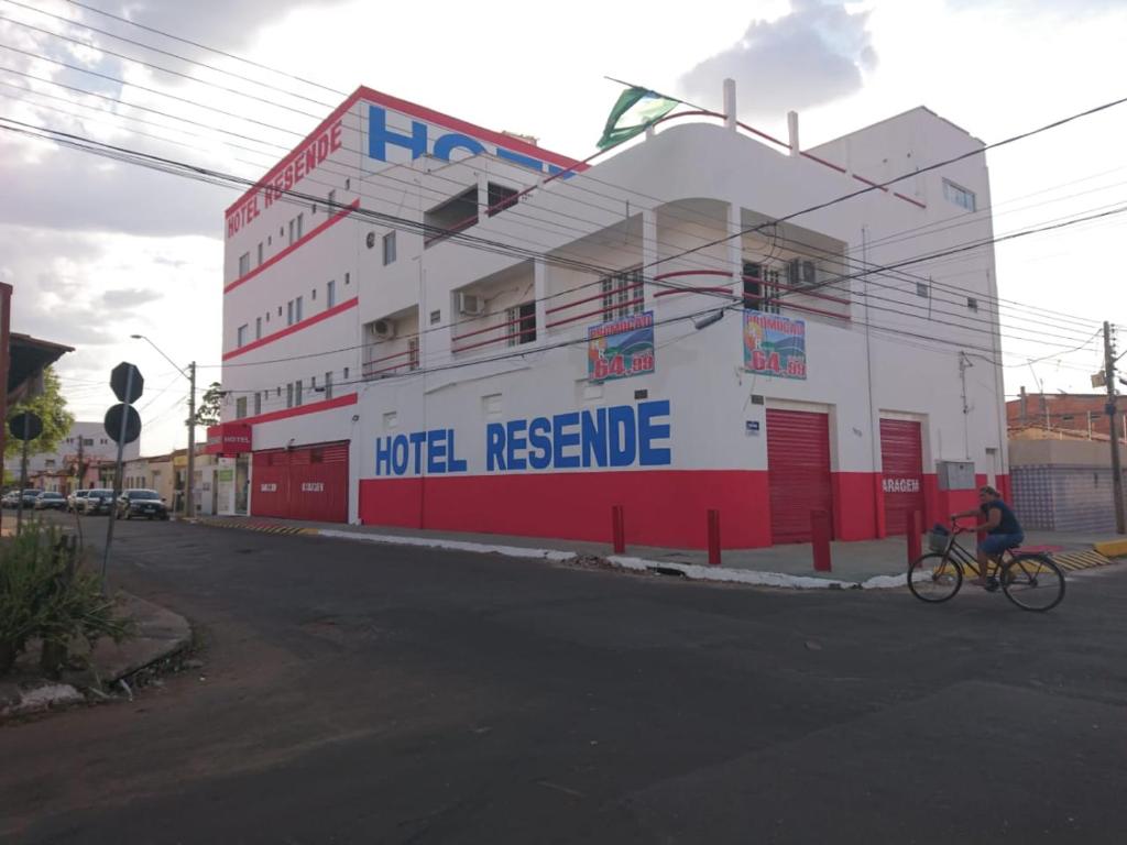 una persona montando una bicicleta delante de un edificio en Hotel Resende, en Imperatriz