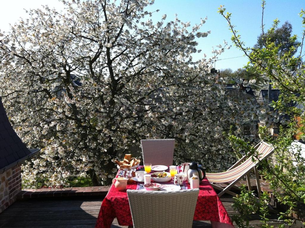 a table with a red table cloth with a tree in the background at Aux Rives de Honfleur in Berville-sur-Mer