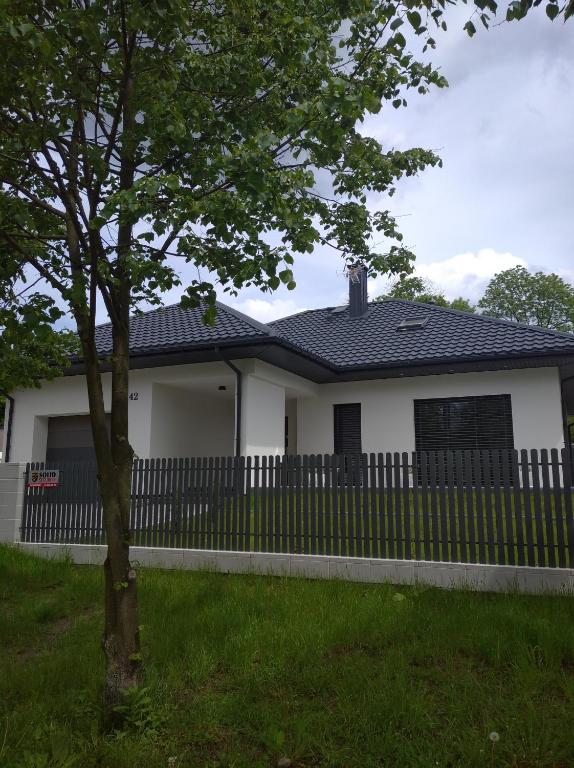 una casa blanca con una valla y un árbol en Strumykowa en Wyszków