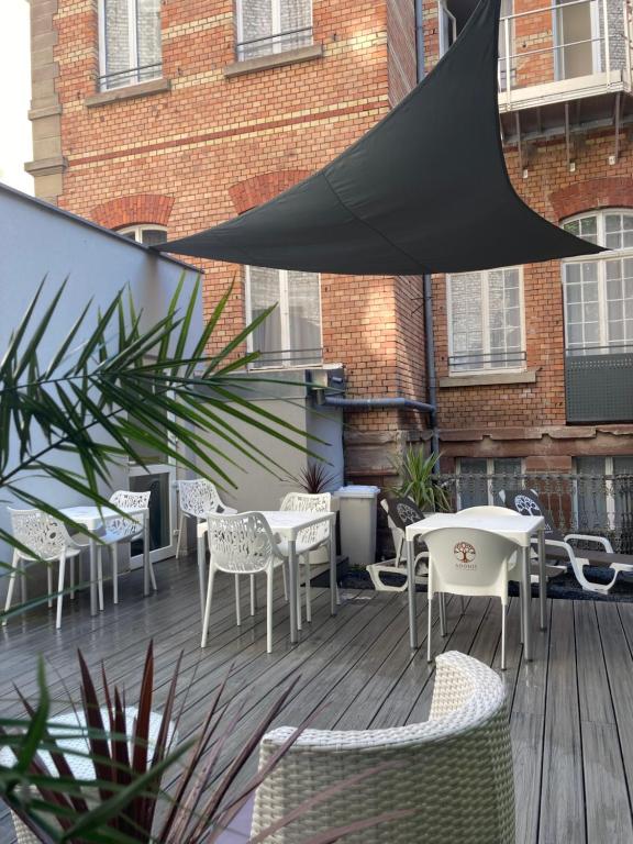 a patio with tables and chairs on a wooden deck at Adonis Hotel Strasbourg in Strasbourg