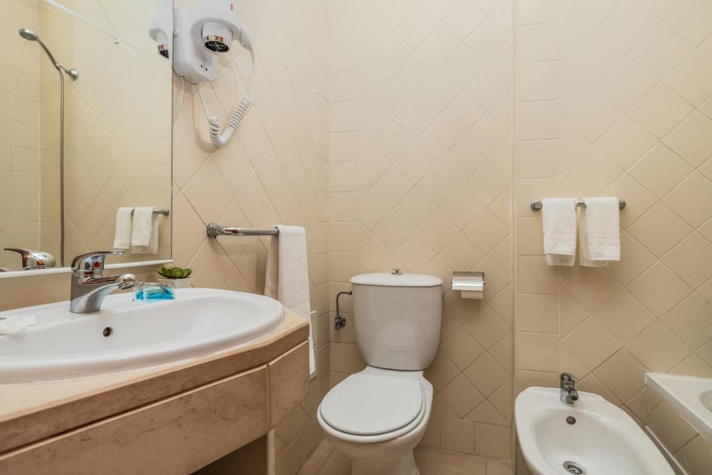 a bathroom with a white toilet and a sink at Hotel Residencial Colibri in Costa da Caparica