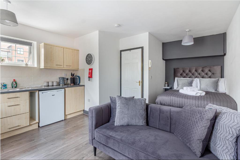 a bedroom with a bed and a couch and a kitchen at Guest Homes - New Street Accommodation in Worcester