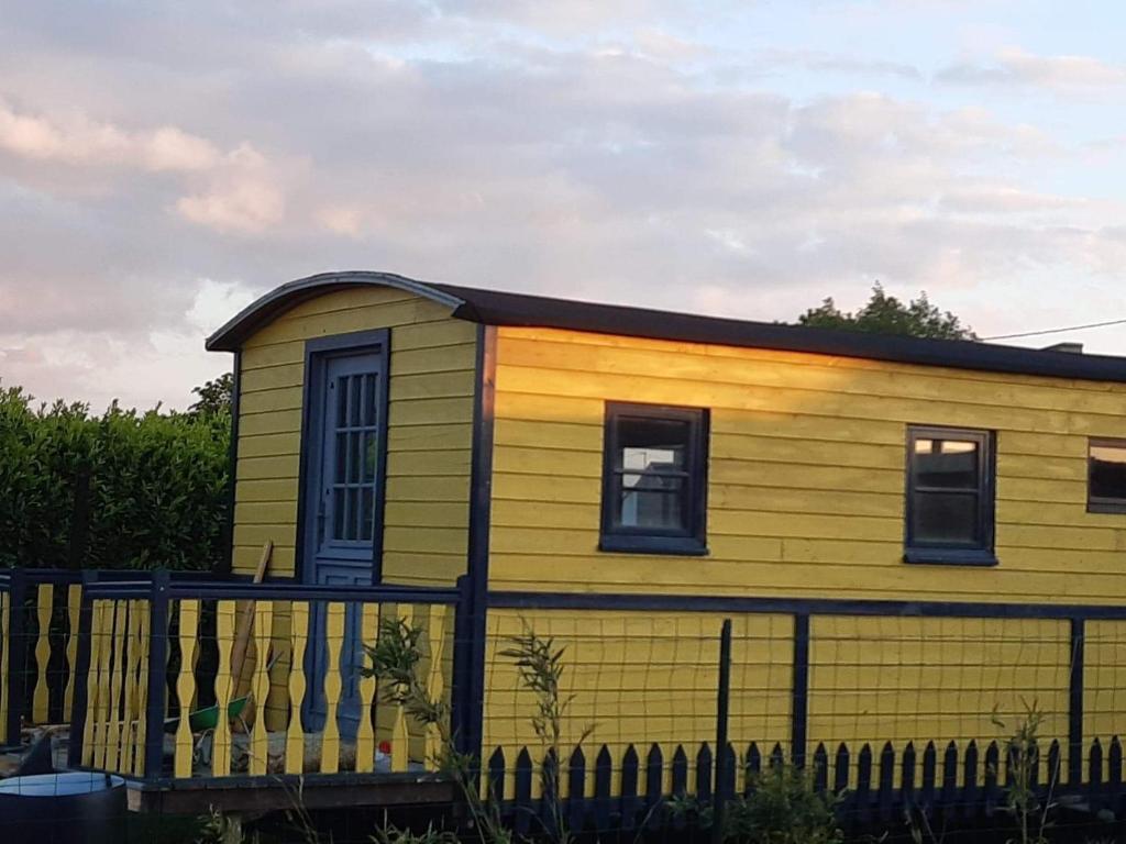 a yellow house with a fence in front of it at Roulotte et Jacuzzi de Rachel au Domaine du Reuze in Winnezeele