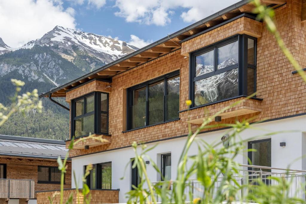 a house with windows with mountains in the background at Chalet Vega - Arlberg Holiday Home in Pettneu am Arlberg