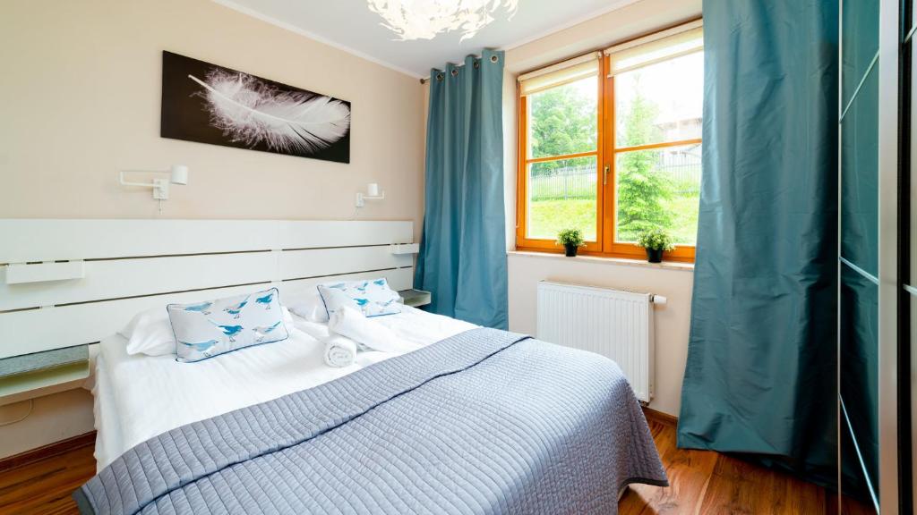 a bedroom with a bed with blue curtains and a window at Apartamenty EverySky - Myśliwska in Karpacz