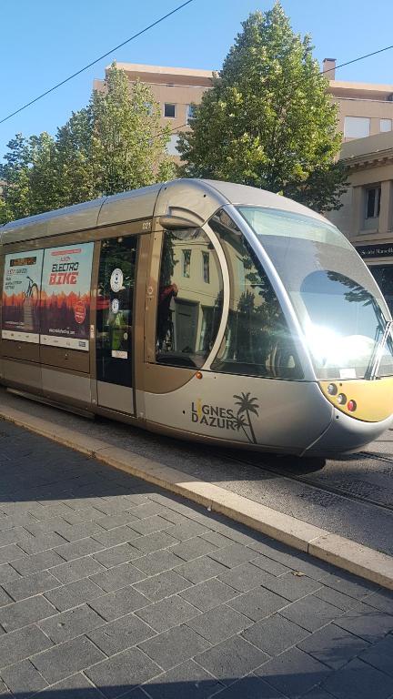 a train is on the tracks on a street at NEW CHEAP PRIVATE ROOM, KITCHEN , OVERWIEUW sea,TRAM on spot, 12 minutes from nice train station with tram , beach in 17 min tram , CHAMBRE PRIVÉE pas cher, cuisine équipée , tram sur place, APERÇU mer, 12 min de la gare de Nice avec le tram, 17 min plage in Nice