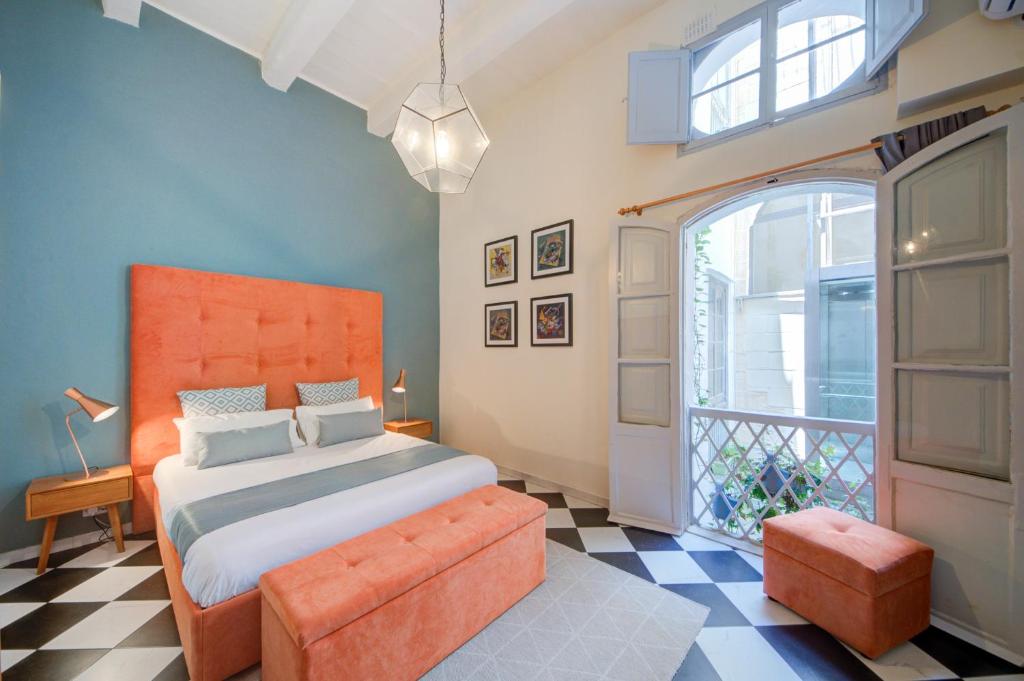 a bedroom with an orange bed and a window at The House in Old Mint Street in Valletta