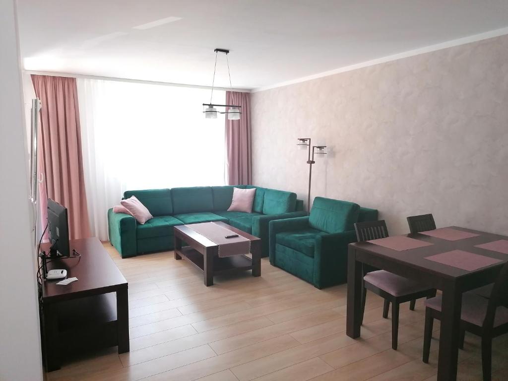 ein Wohnzimmer mit einem grünen Sofa und einem Tisch in der Unterkunft Apartament POLANKI in Kołobrzeg