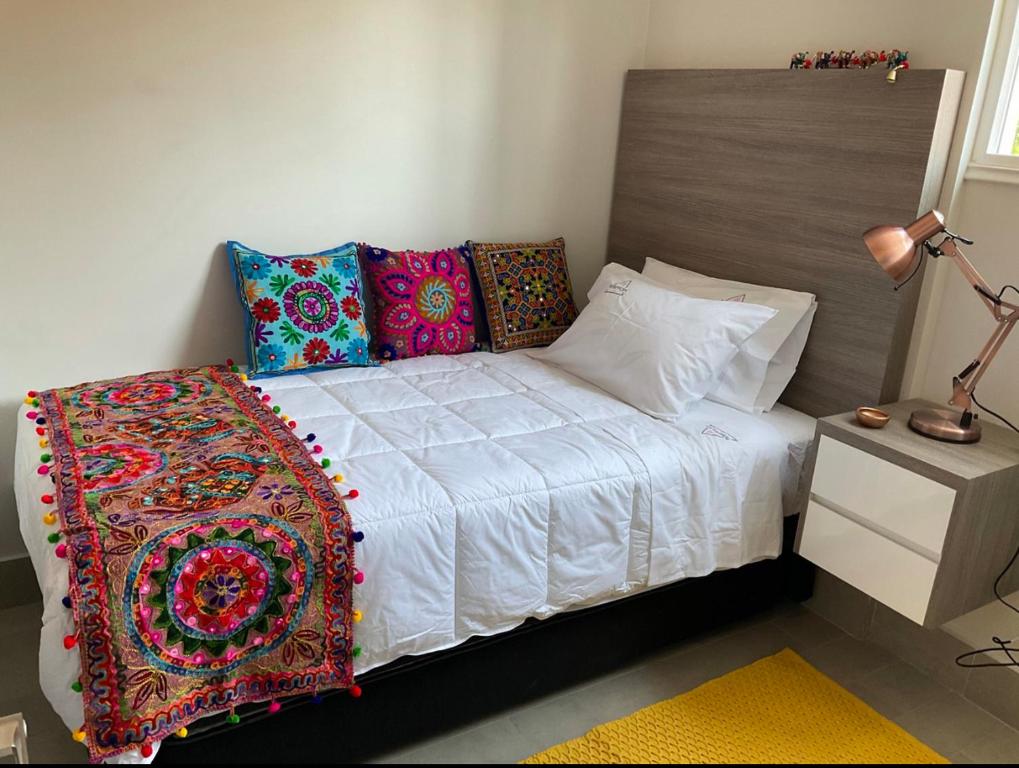 um quarto com uma cama com almofadas coloridas em Apartament Condo Amueblado, ENCOMENDEROS 200 El Golf, Las Condes Santiago con vista al Costanera Center em Santiago