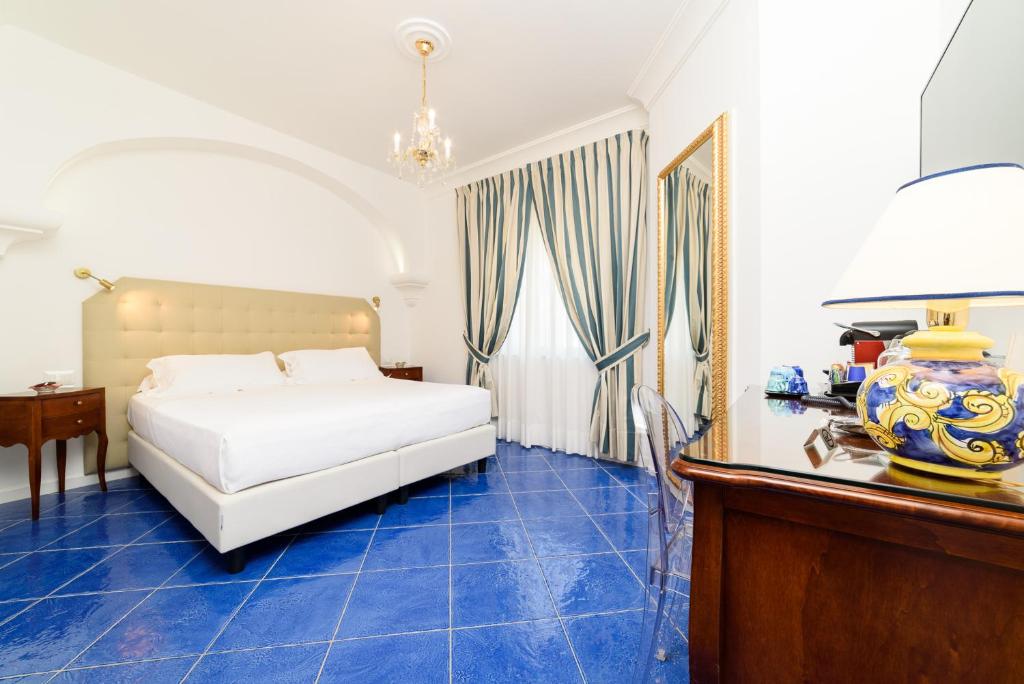 a bedroom with a white bed and blue tile floors at La Casa di Paolo Casa di Charme in Marina di Camerota