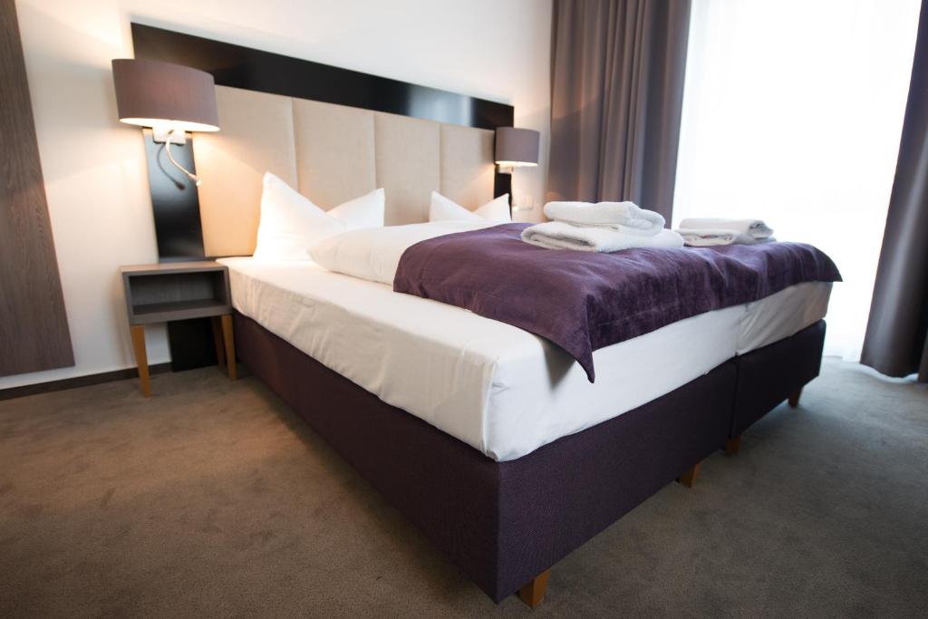 een slaapkamer met een groot bed en een paarse deken bij Goethe Business Hotel by Trip Inn in Frankfurt am Main