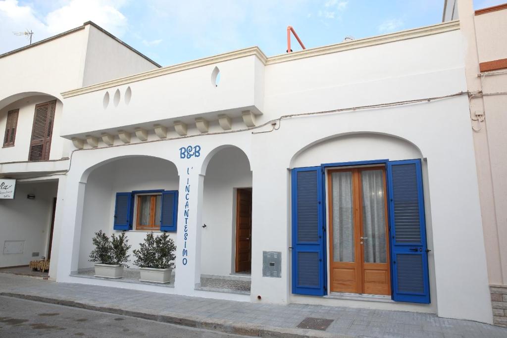 un edificio blanco con puertas azules en una calle en B&b L'Incantesimo, en Morciano di Leuca