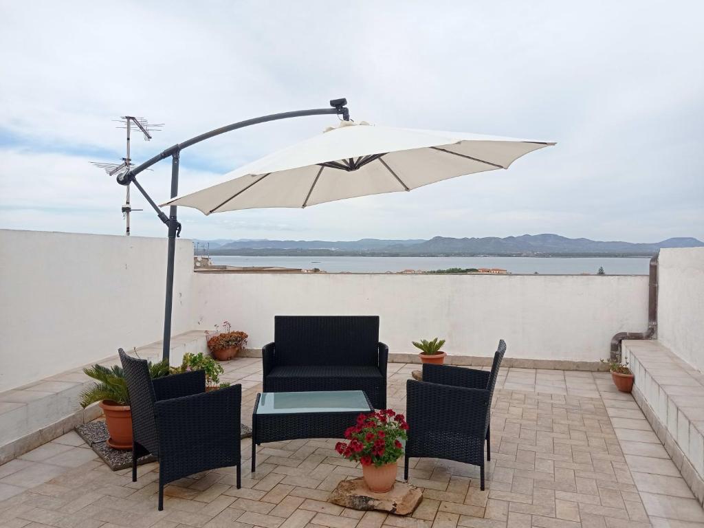 patio con tavolo, sedie e ombrellone di B&B Belvedere a SantʼAntìoco