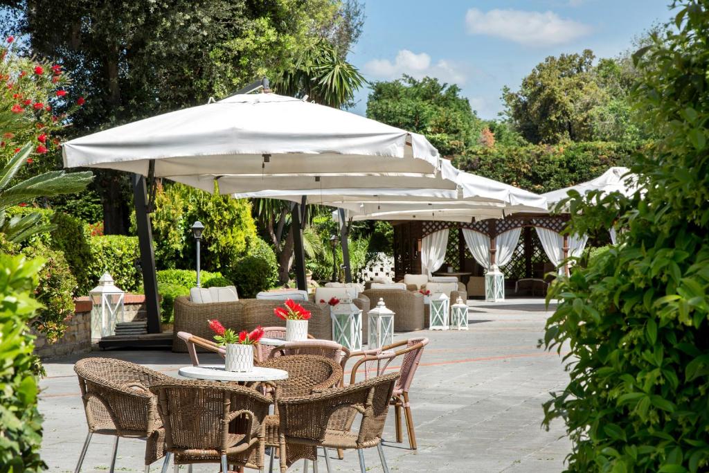 a patio with tables and chairs with umbrellas at Montespina Park Hotel in Naples