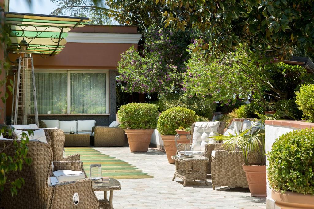 a patio with wicker chairs and tables and plants at Montespina Park Hotel in Naples