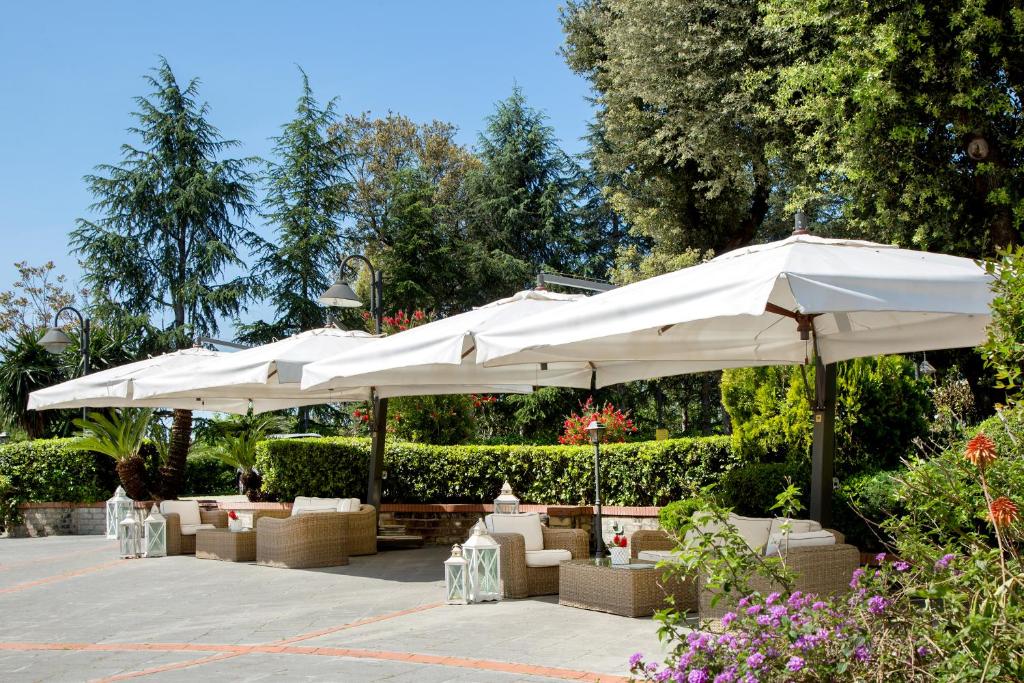 a patio with white umbrellas and tables and chairs at Montespina Park Hotel in Naples
