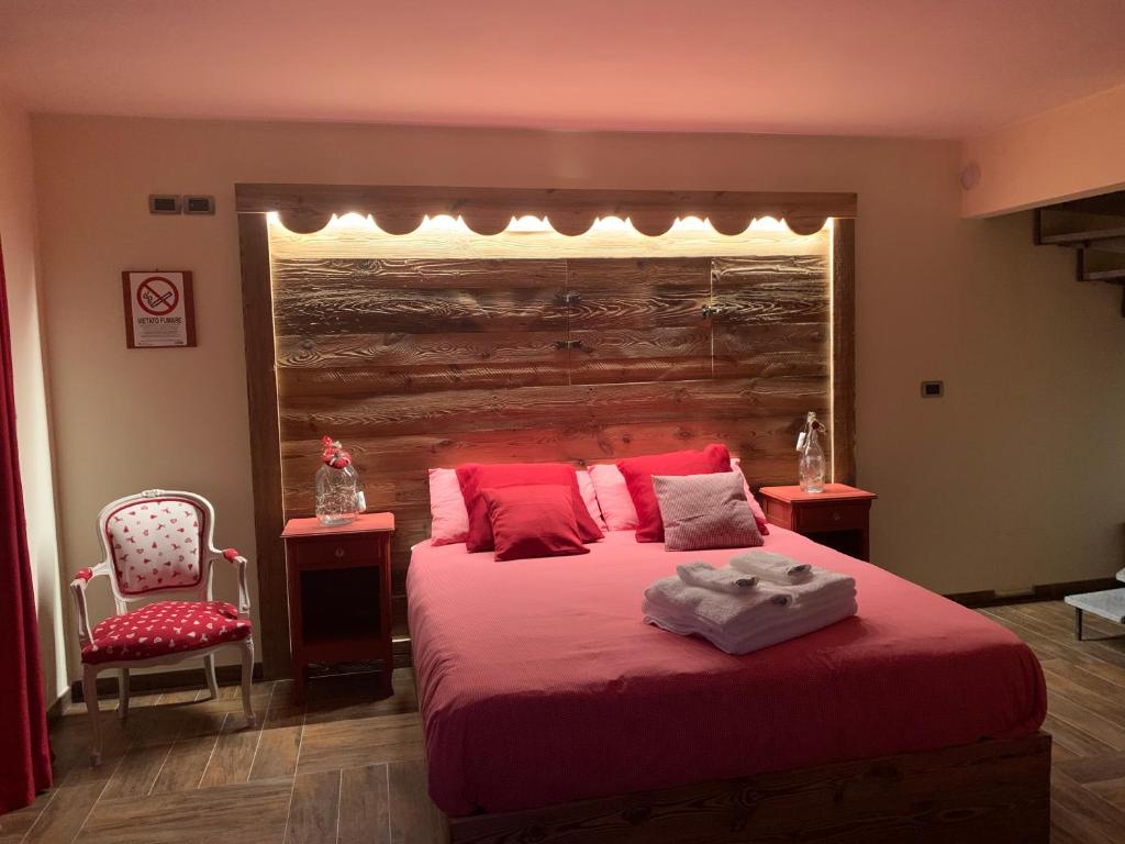 a bedroom with a large bed with red sheets and a chair at Ca di Nadia in Aosta