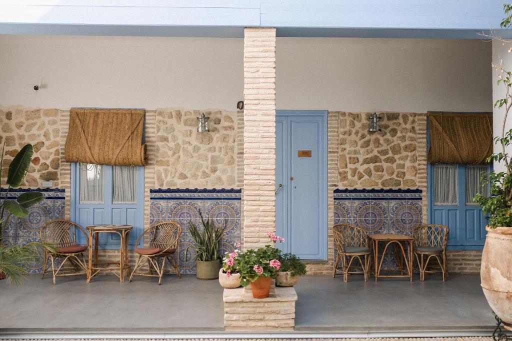 eine Terrasse mit Stühlen, Tischen und blauen Türen in der Unterkunft CASA SIRFANTAS in Córdoba