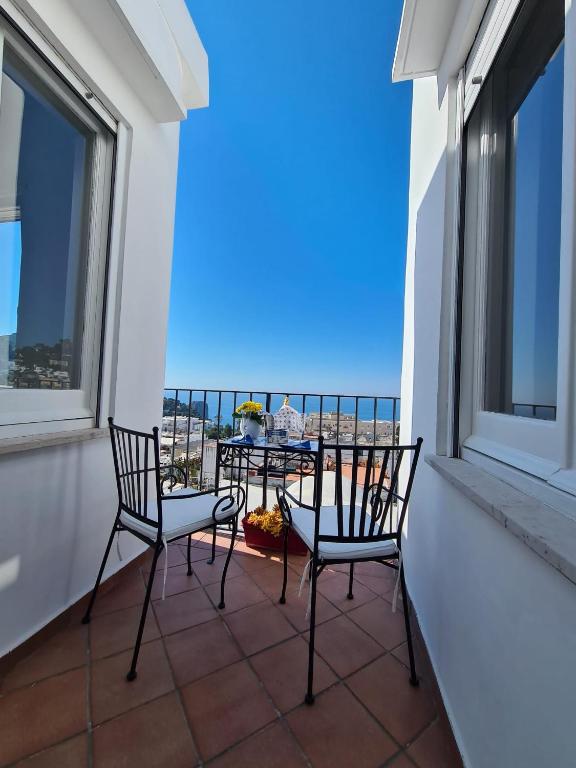 balkon z dwoma krzesłami i stołem w obiekcie Casa Leucosia Suites w mieście Capri