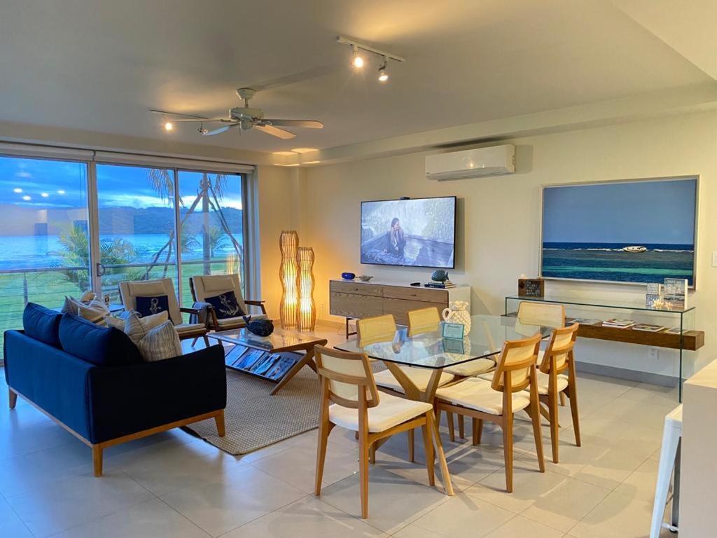 sala de estar con mesa, sillas y TV en Azuero Lodge: Luxury Beachfront condo- Playa Venao, en Playa Venao