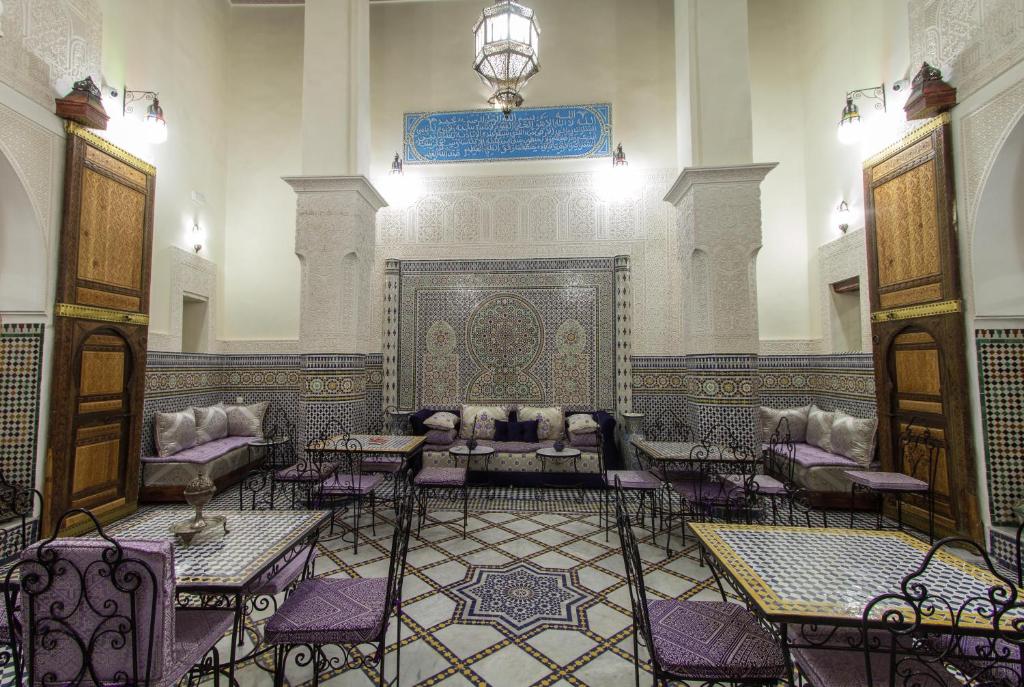 a room with tables and chairs in a building at Riad Taryana in Fez