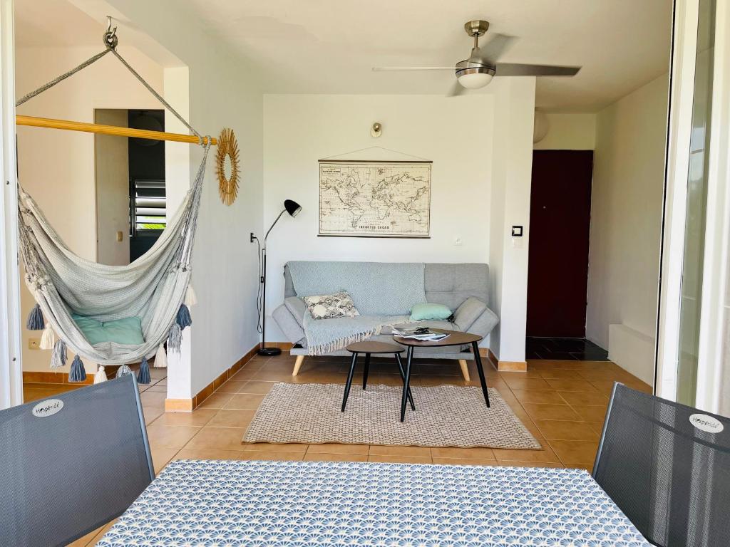 een woonkamer met een bank en een tafel bij Appartement vue mer, piscine, dans quartier prisé de Gosier in Le Gosier