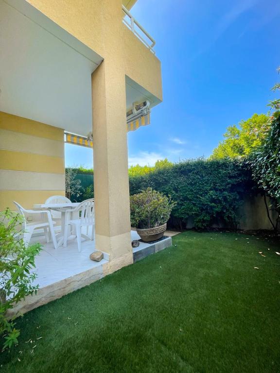 une terrasse avec des tables et des chaises blanches sur une pelouse dans l'établissement Superb Apartment With Garden Near The Sea, à Fréjus