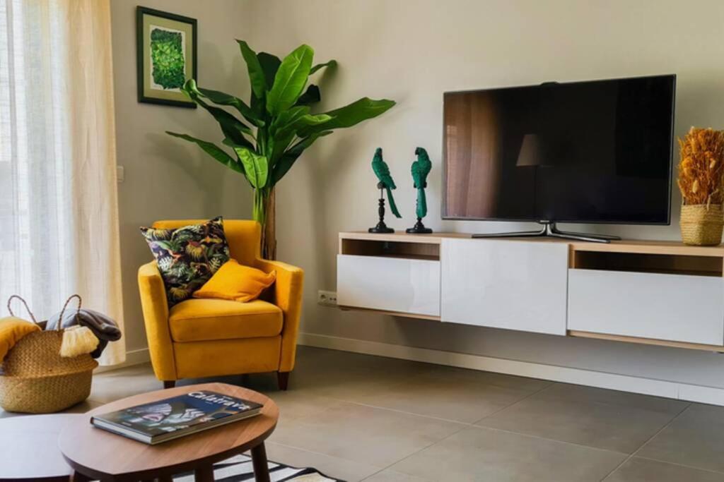 a living room with a tv and a yellow chair at Comfort Zone beach apartment in Quarteira
