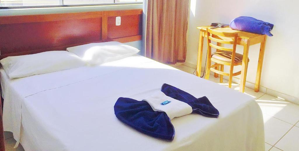 ein Hotelzimmer mit einem Bett und einem Bademantel. in der Unterkunft Pecafe Hotel in Manhuaçu