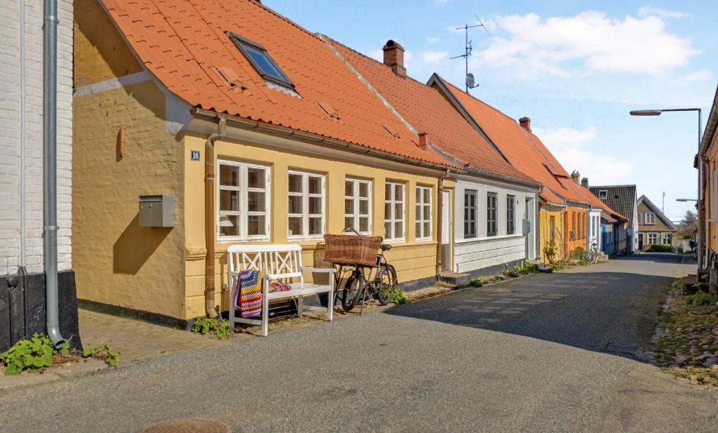 a yellow building with an orange roof on a street at Hyggeligt gammelt fiskerhus i Marstal in Marstal