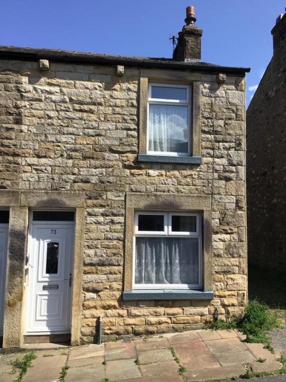 a brick house with two windows and a white door at Cosy end terrace in Lancaster