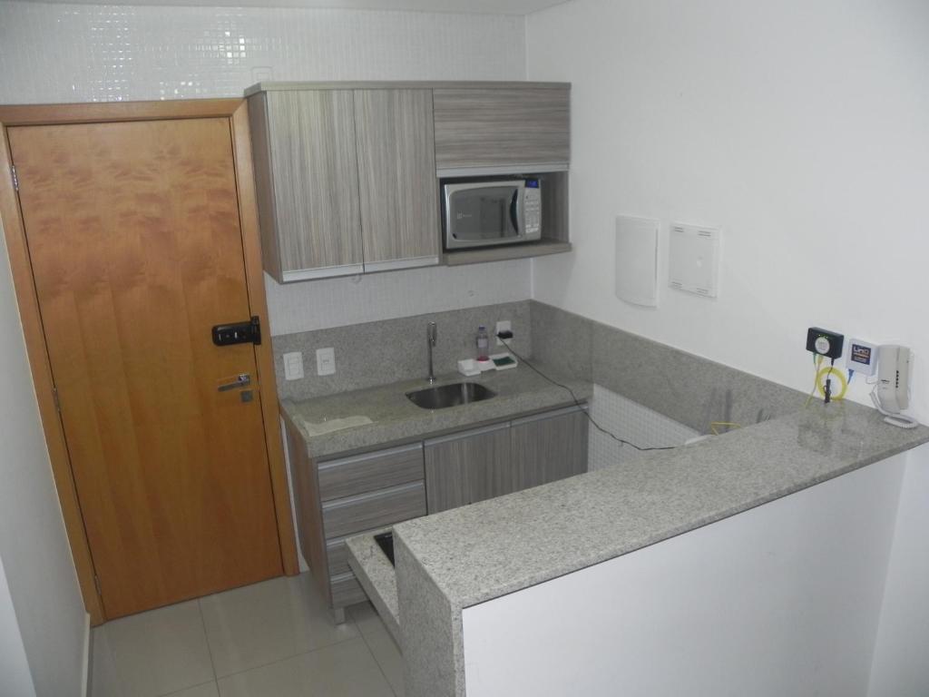 uma pequena cozinha com pia e micro-ondas em Flat Essenciale Style 1506 em Goiânia