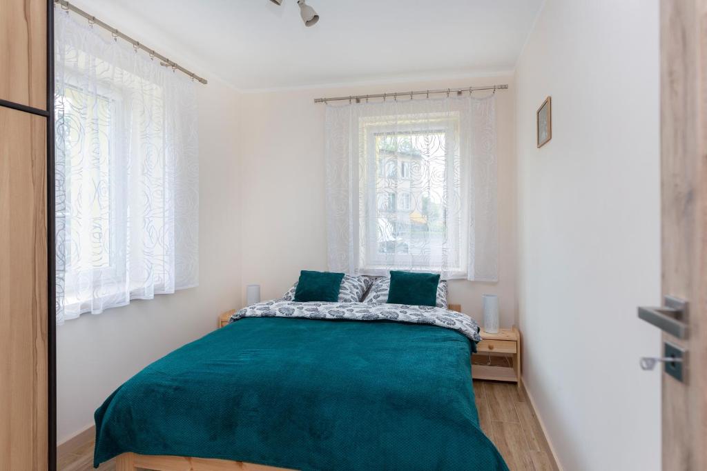 - une chambre avec un lit et une couverture verte dans l'établissement przystanek Kudowa, à Kudowa-Zdrój