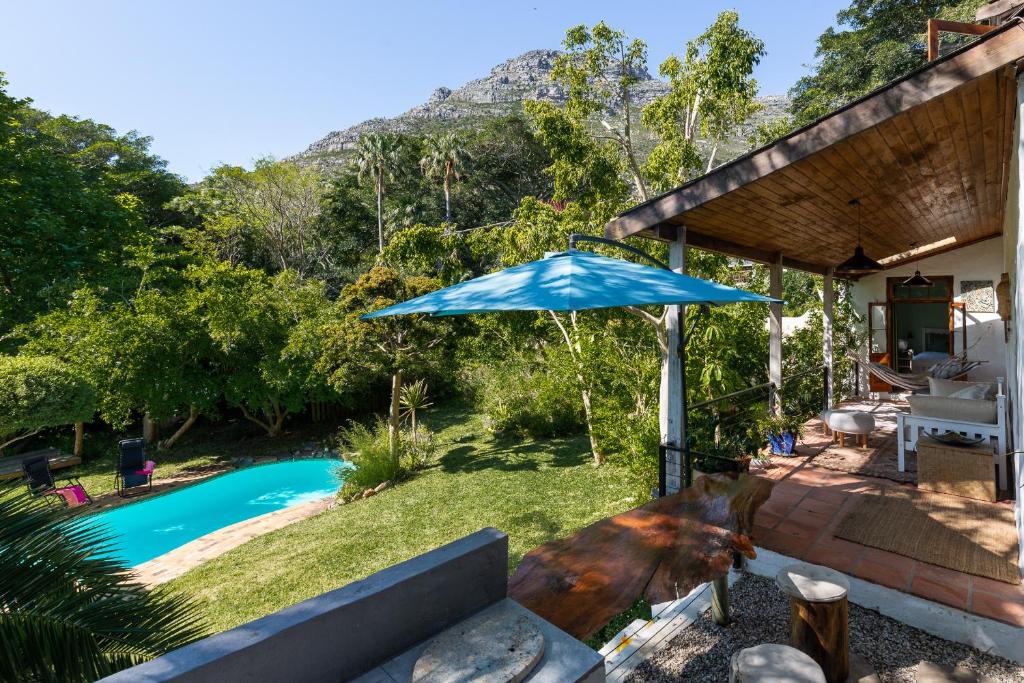 a patio with a blue umbrella next to a pool at ZenCapeTown Holiday House in Hout Bay