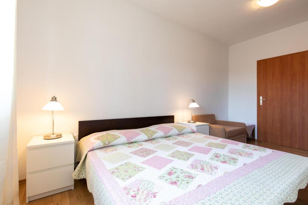 a bedroom with a bed with a pink and white quilt at Apartmani Tamara in Sveti Anton
