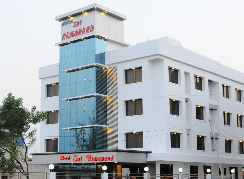 un edificio blanco con un cartel. en Hotel Sai Ramanand, en Shirdi